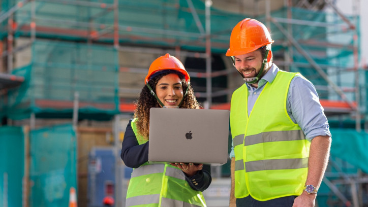 A women and a man on a construction site looking at the laptop screen