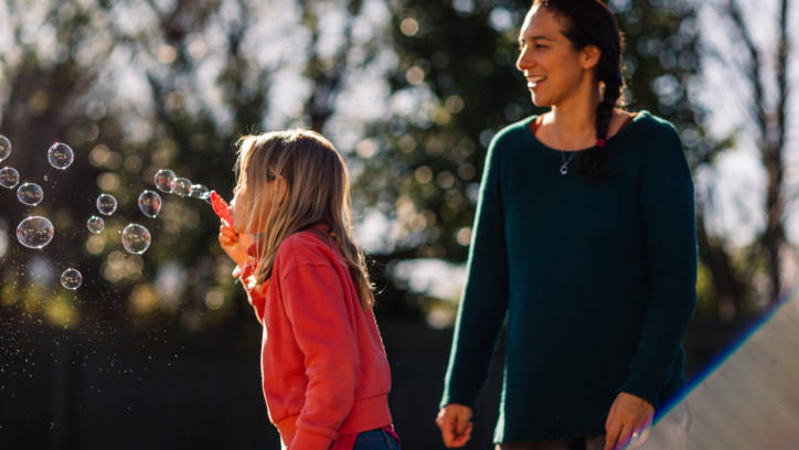 Child blows bubbles with adult