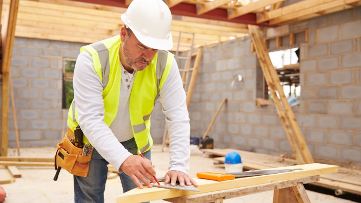 Builder measuring timber on a building site