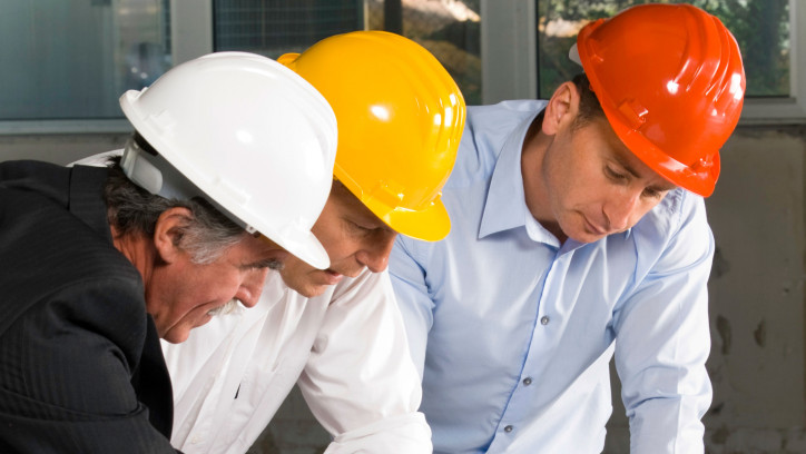 Three building professionals looking at design plans