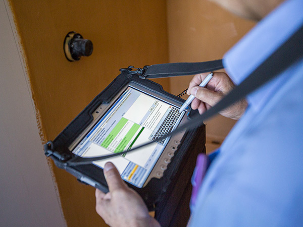Council inspector Council inspector recording details on tablet device while conducting inspection