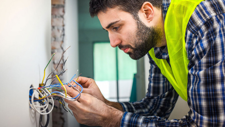 Man doing a wiring job through a wall