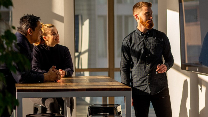 Three people suffused in golden light examining a screen on a wall