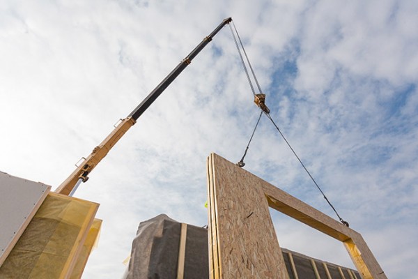 Image showing a structural insulated panel being lifted onto a building site by a crane