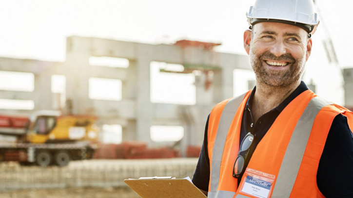 Construction worker on construction site, with clipboard.