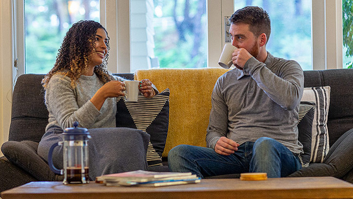 Woman and man drinking coffee on couch