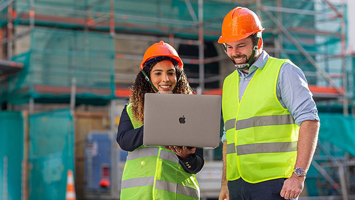 A women and a man on a construction site looking at the laptop screen