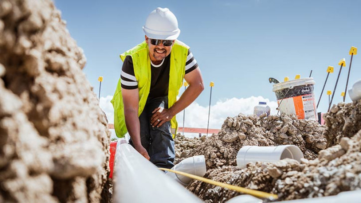 Drainlayer place pipes in dirt.