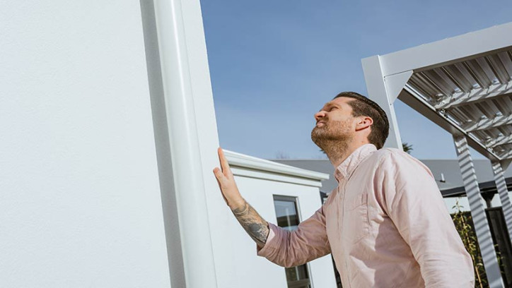 a homeowner looking at a house with his hand touching the white wall